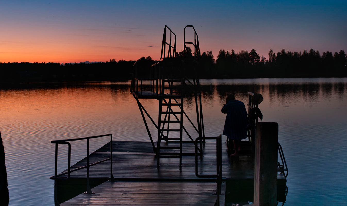 The diving tower at Lossi Beach is silhouetted against an orange sunset sky.