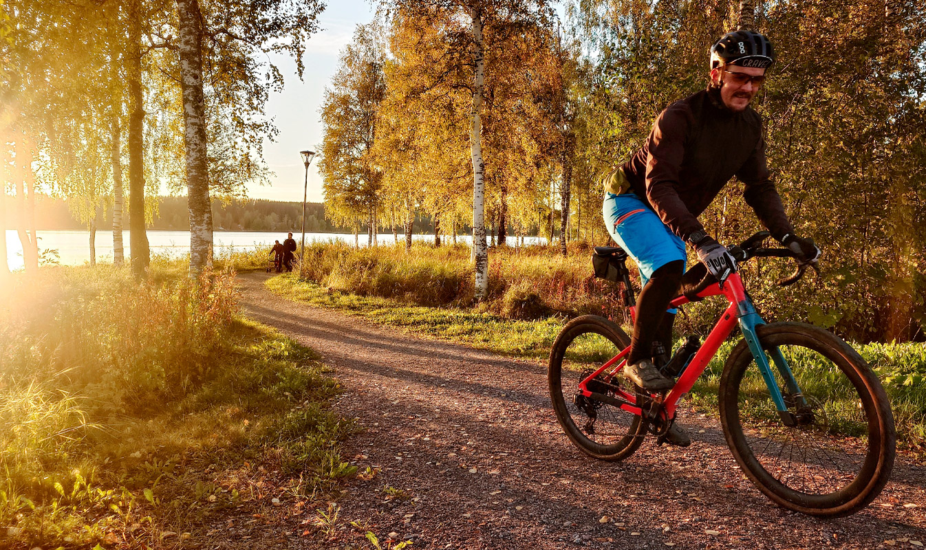 A person cycles along the shore with the sun shining from behind. 