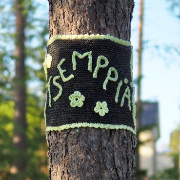 “Cheer up!” yarn graffiti tied around a tree.