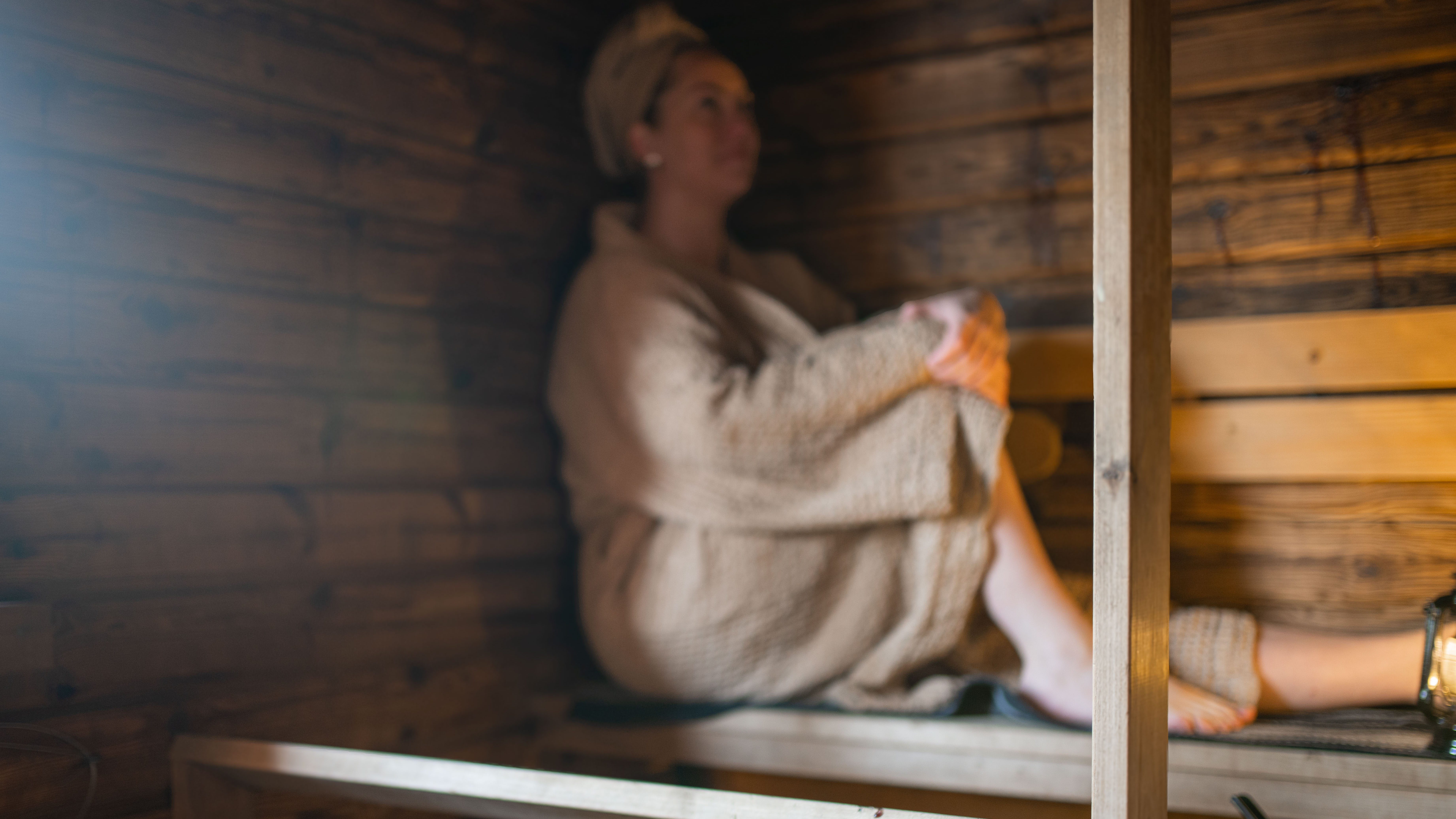 A person sits on the sauna bench.