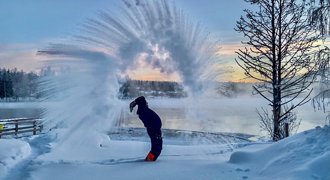 A man throws hot water into the air in winter frost near the Häränvirta ice swimming spot.