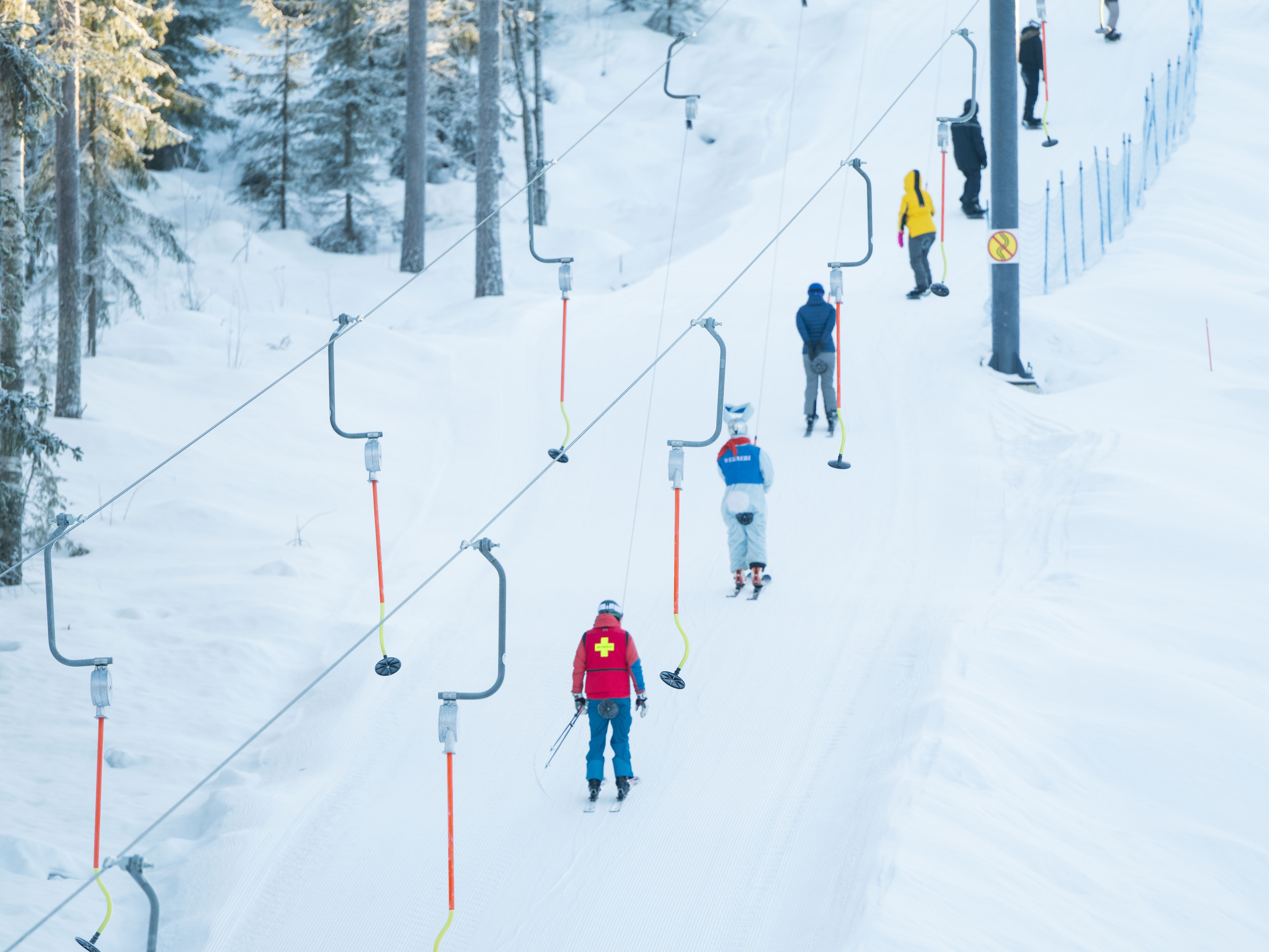 People riding a ski lift up the slope.

