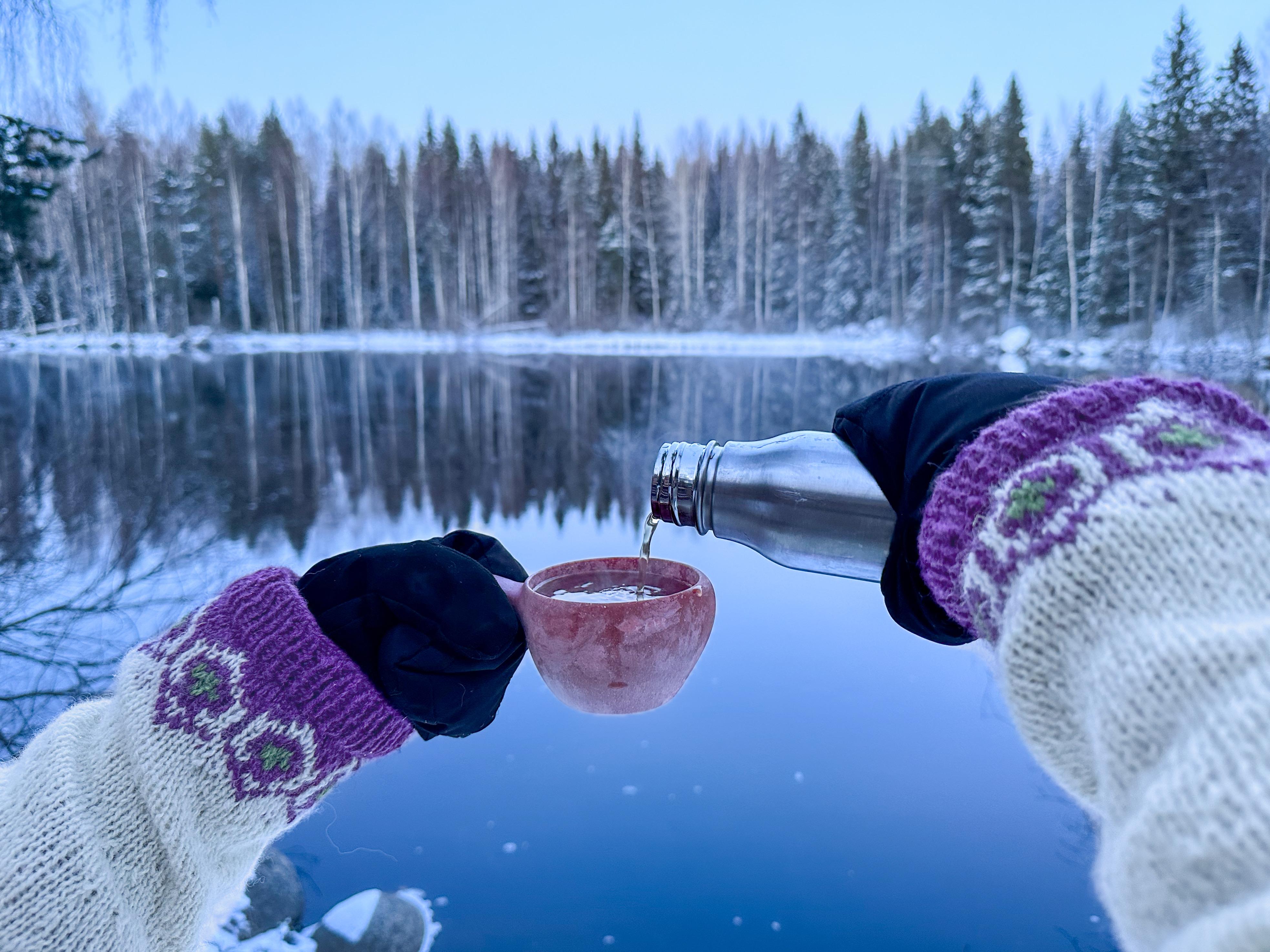 Enjoying tea from a kuksa by the rapids
