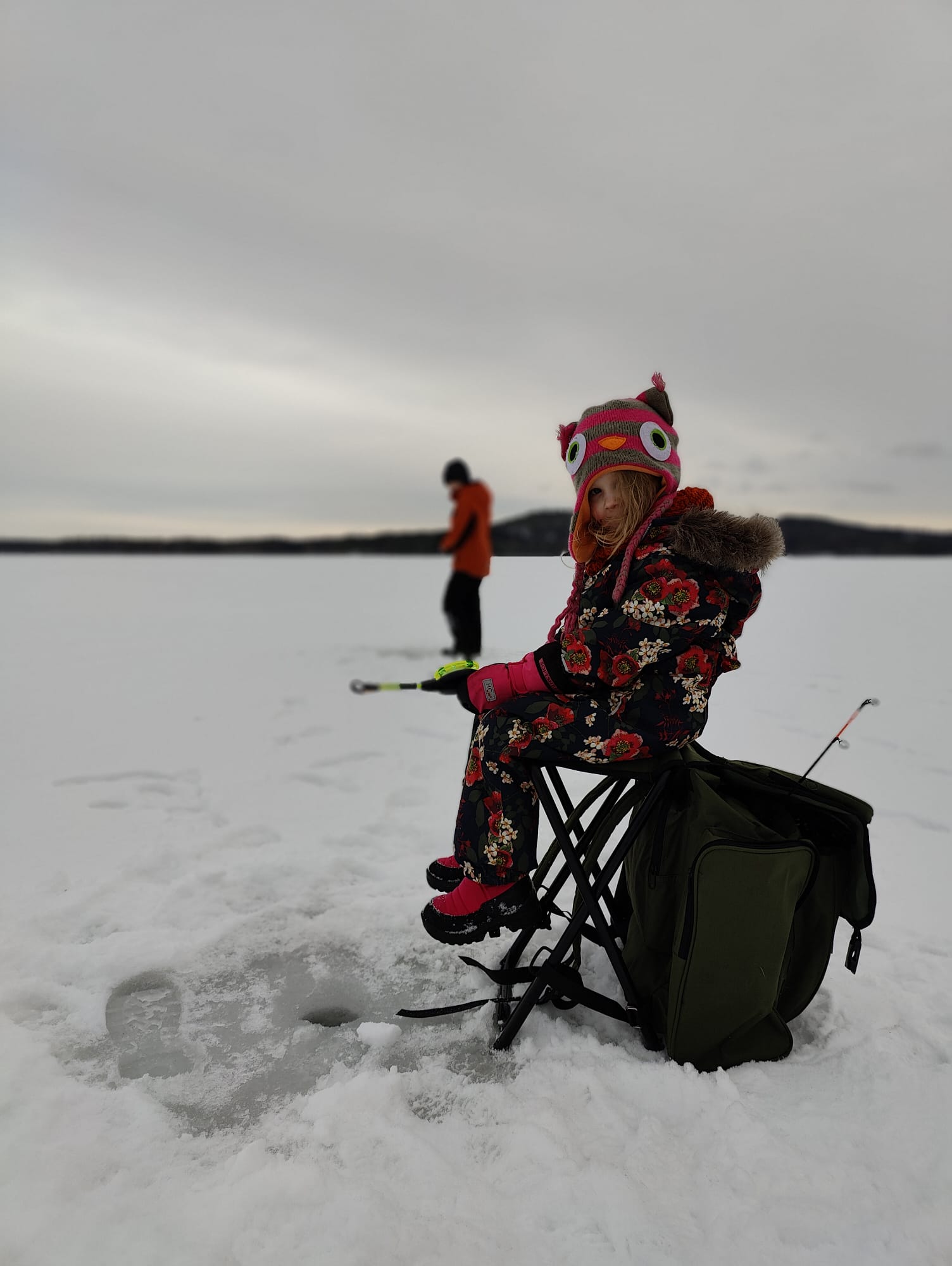 A child ice fishing on the ice.